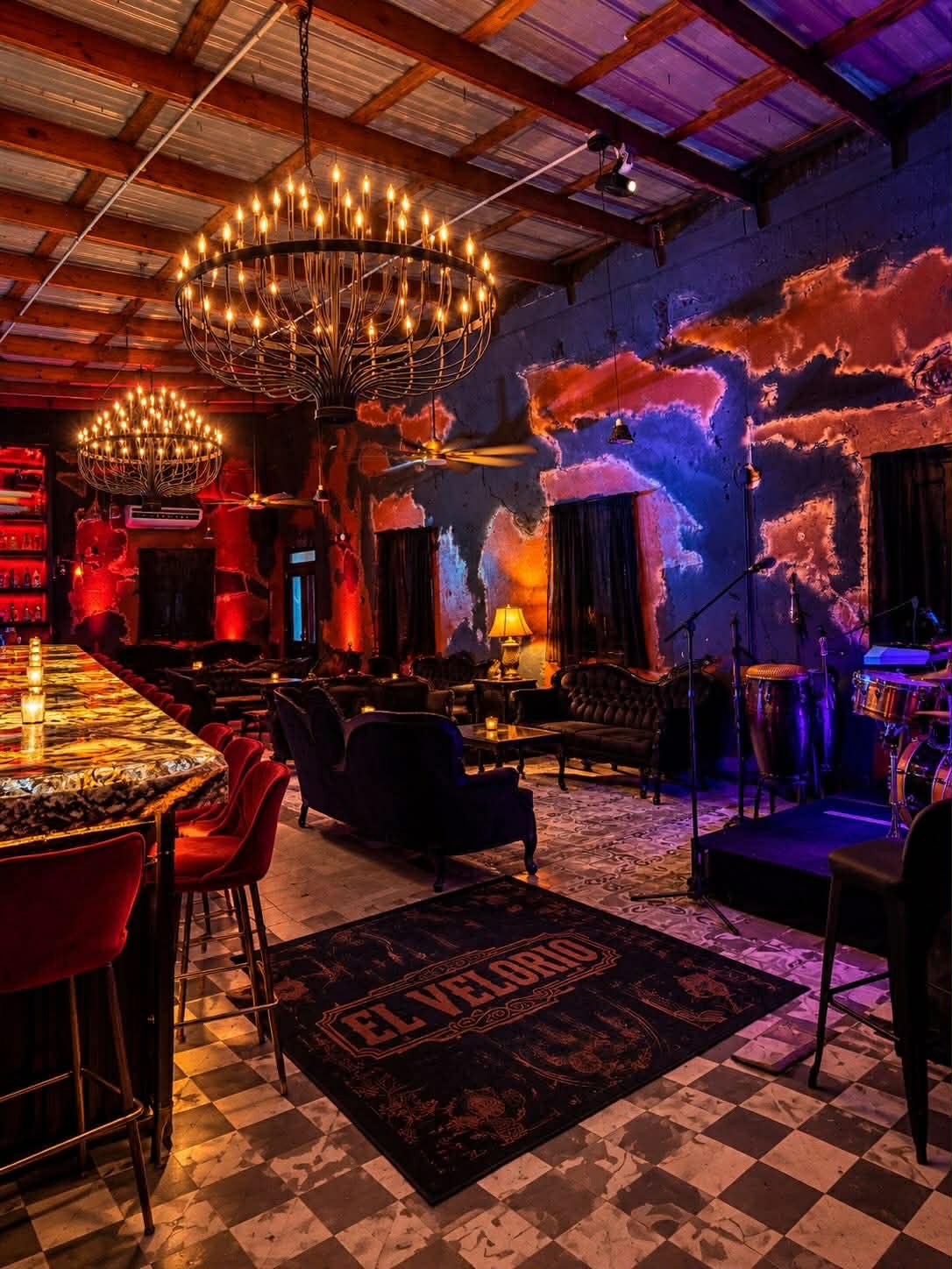 Salón de El Velorio con candelabros de velas, sofás victorianos y barra de ónix iluminada